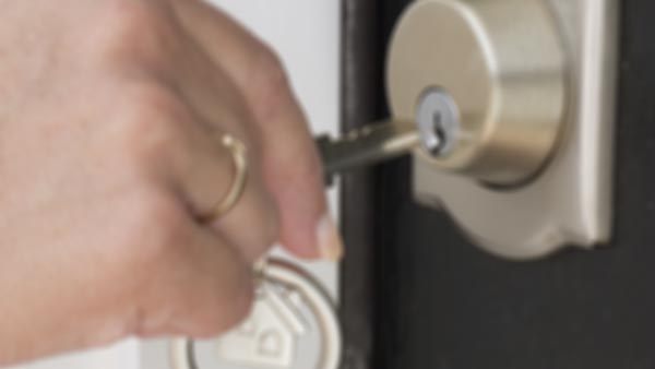 close up on hand inserting a key into a door lock